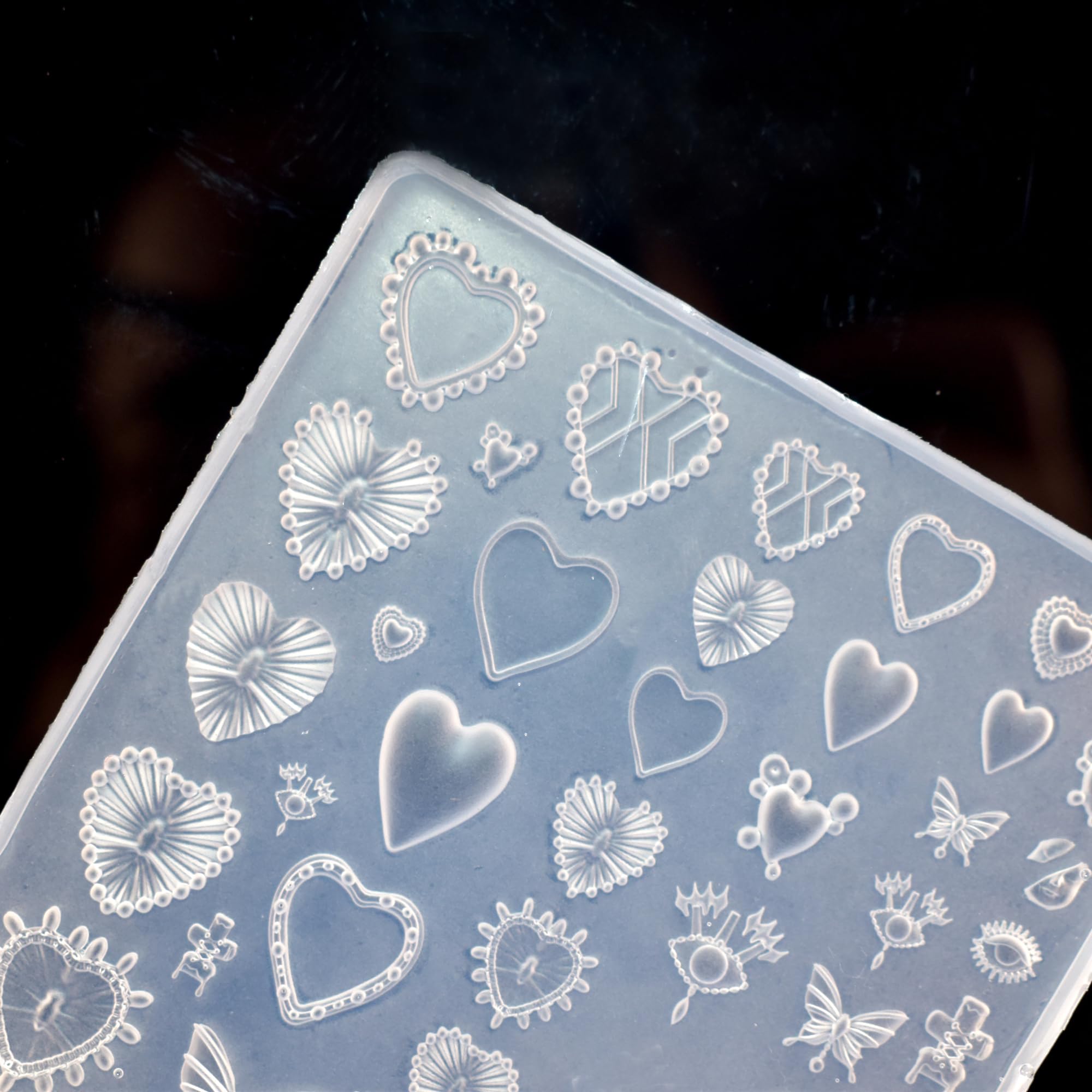 Completed 3D butterfly and heart charms placed alongside the transparent LIFOOST modeling template on a manicure workspace