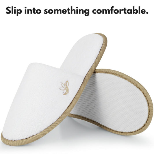 Twelve pairs of individually wrapped white closed toe hotel slippers displayed together