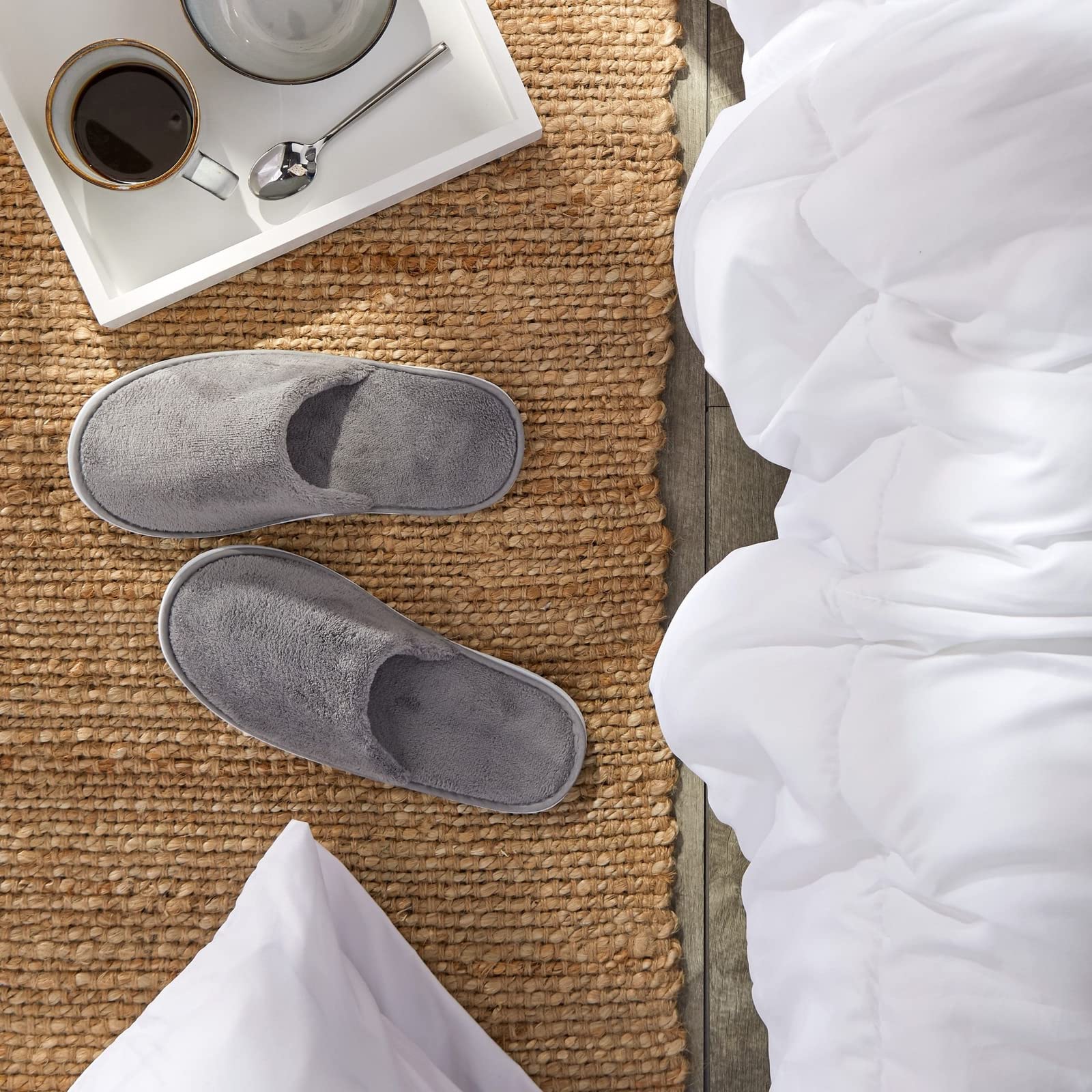 Bulk pack of twelve pairs of individually wrapped gray spa slippers arranged neatly for hospitality use.