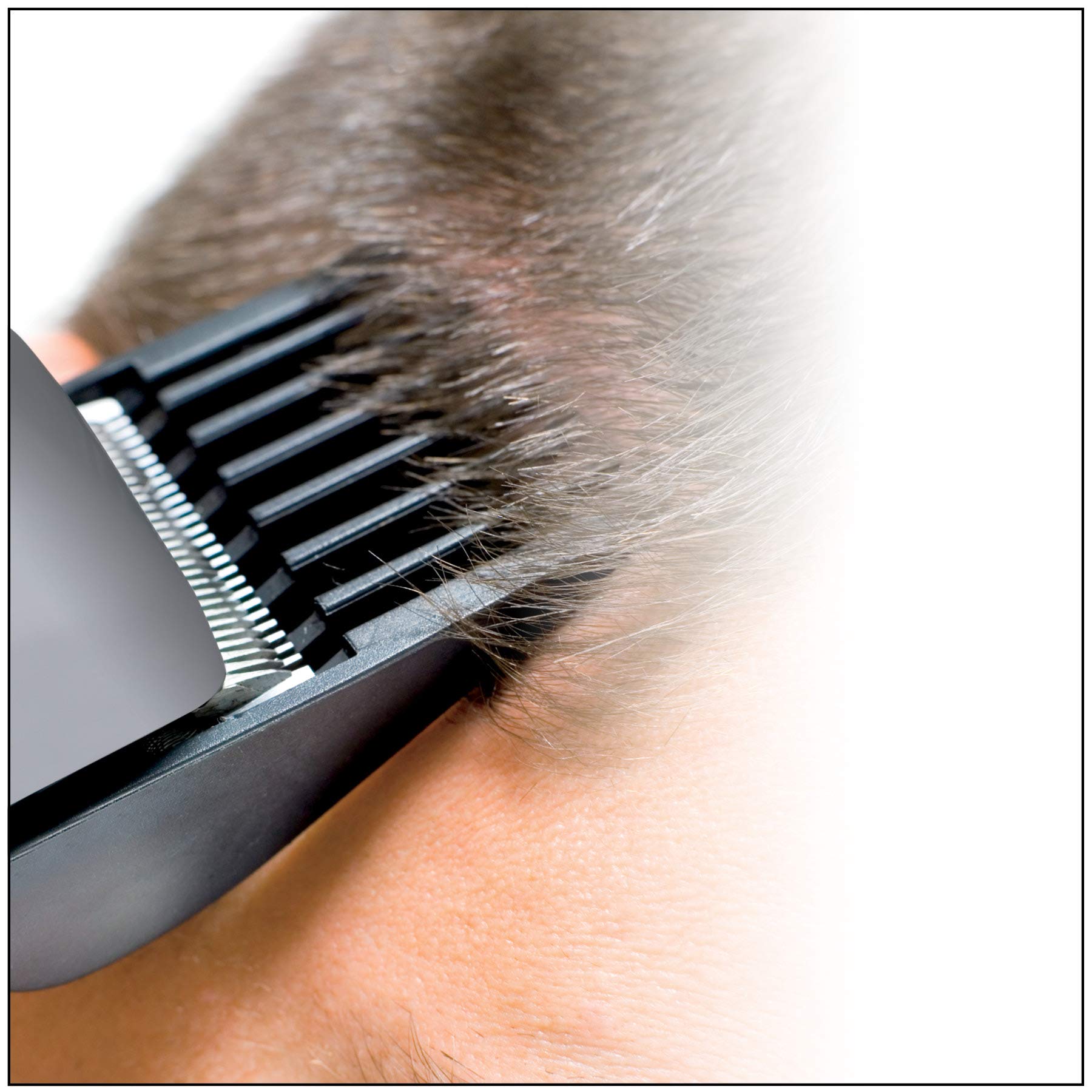 Man using the ConairMAN corded hair clipper to trim sideburns with a guide comb attachment attached.