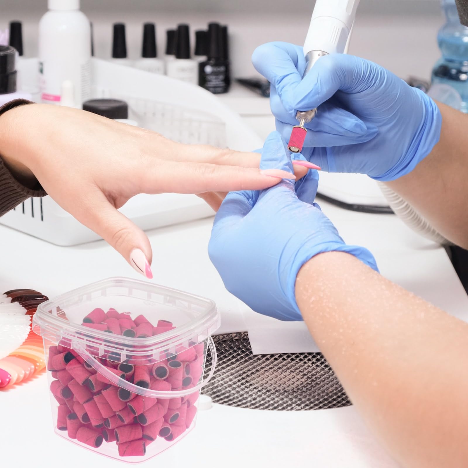 Compact clear storage bucket filled with two hundred pieces of pink manicure sanding bands.