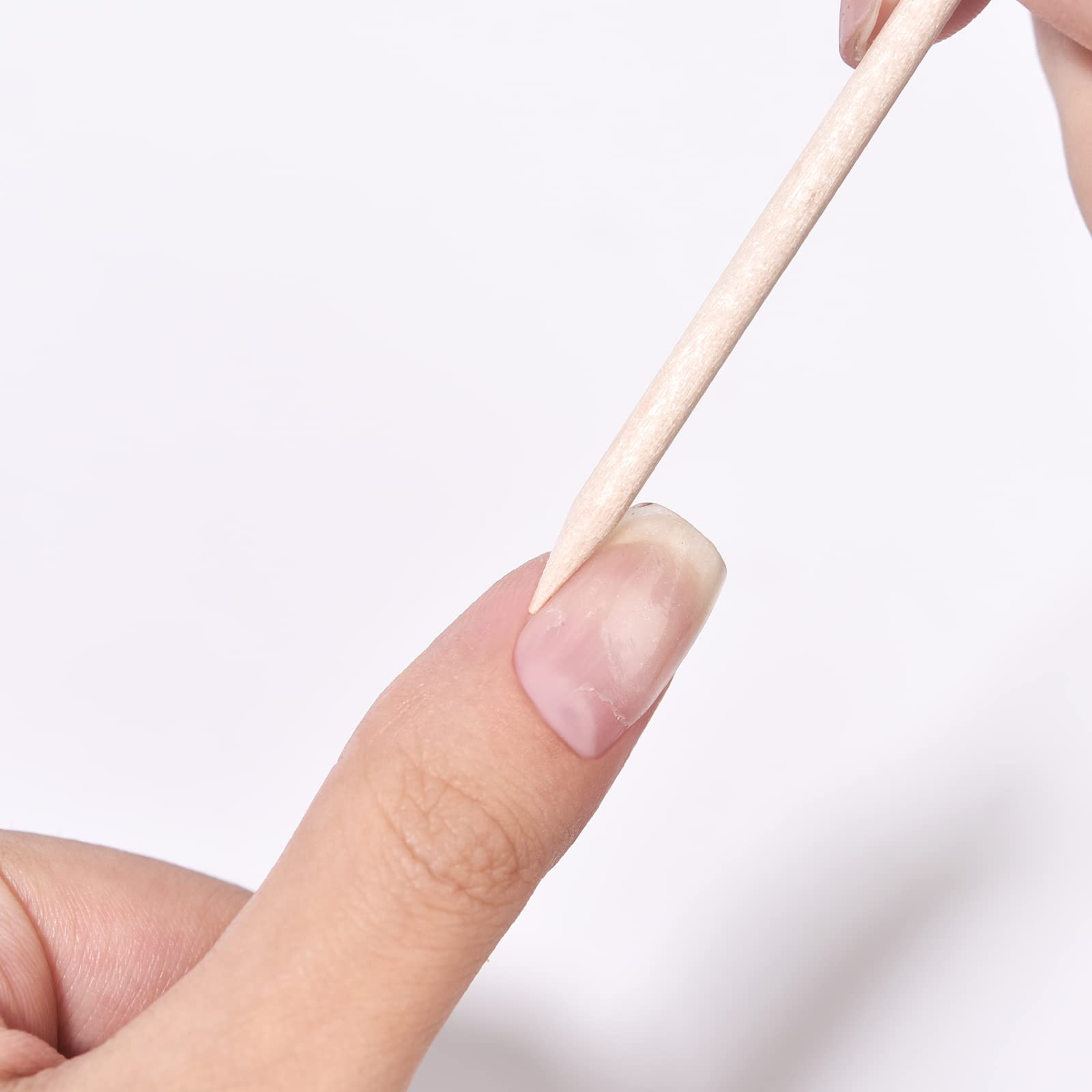 Flat end of orange wood stick pushing back cuticle