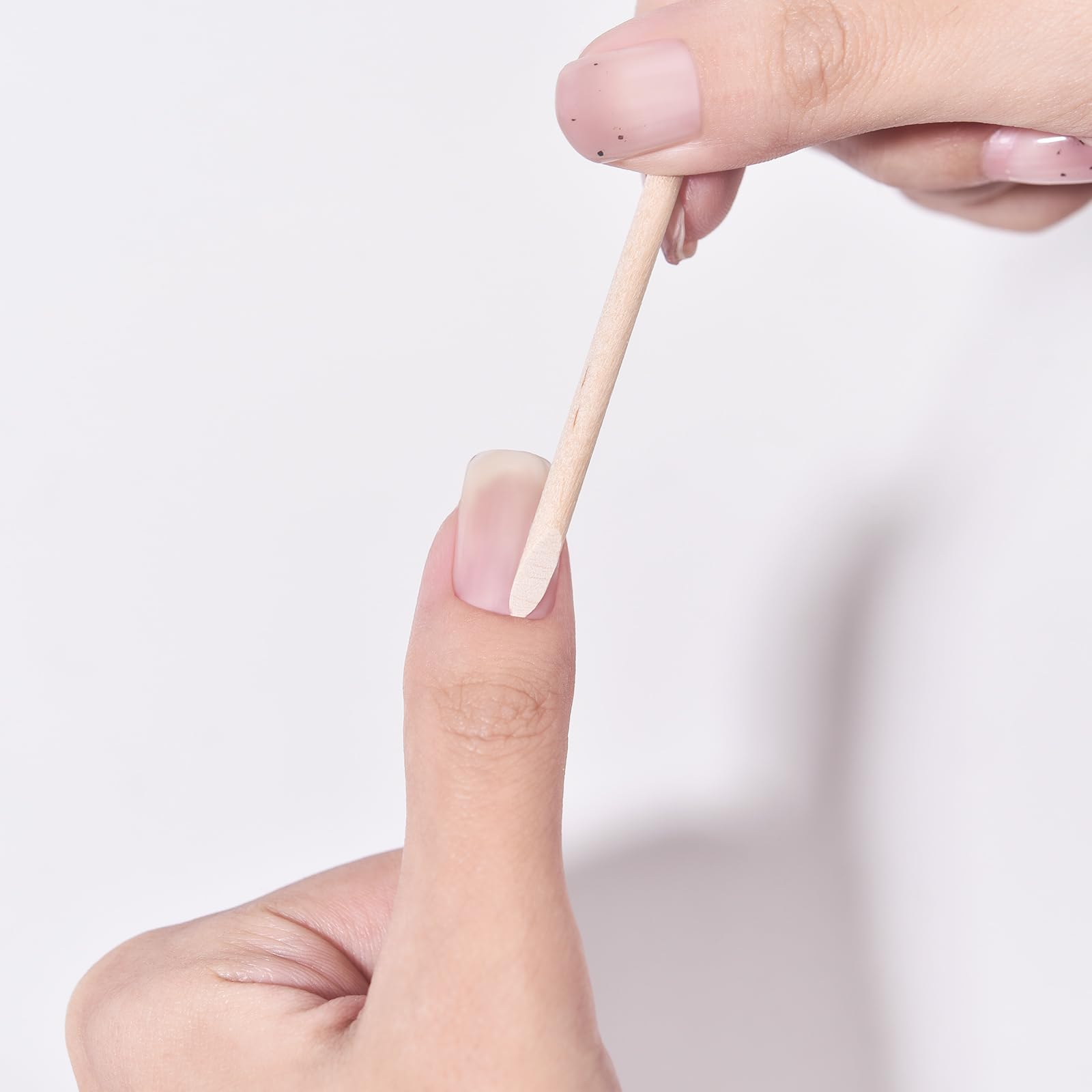Using flat end of orange stick to push back cuticle