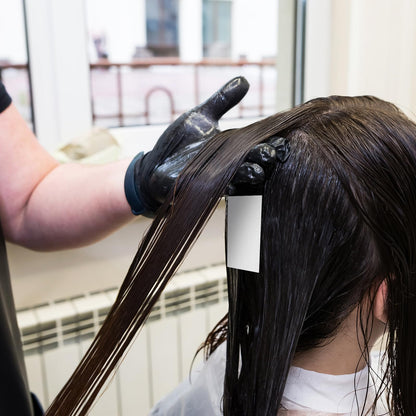 White thin mesh hairdressing end wraps being applied to hair rollers.
