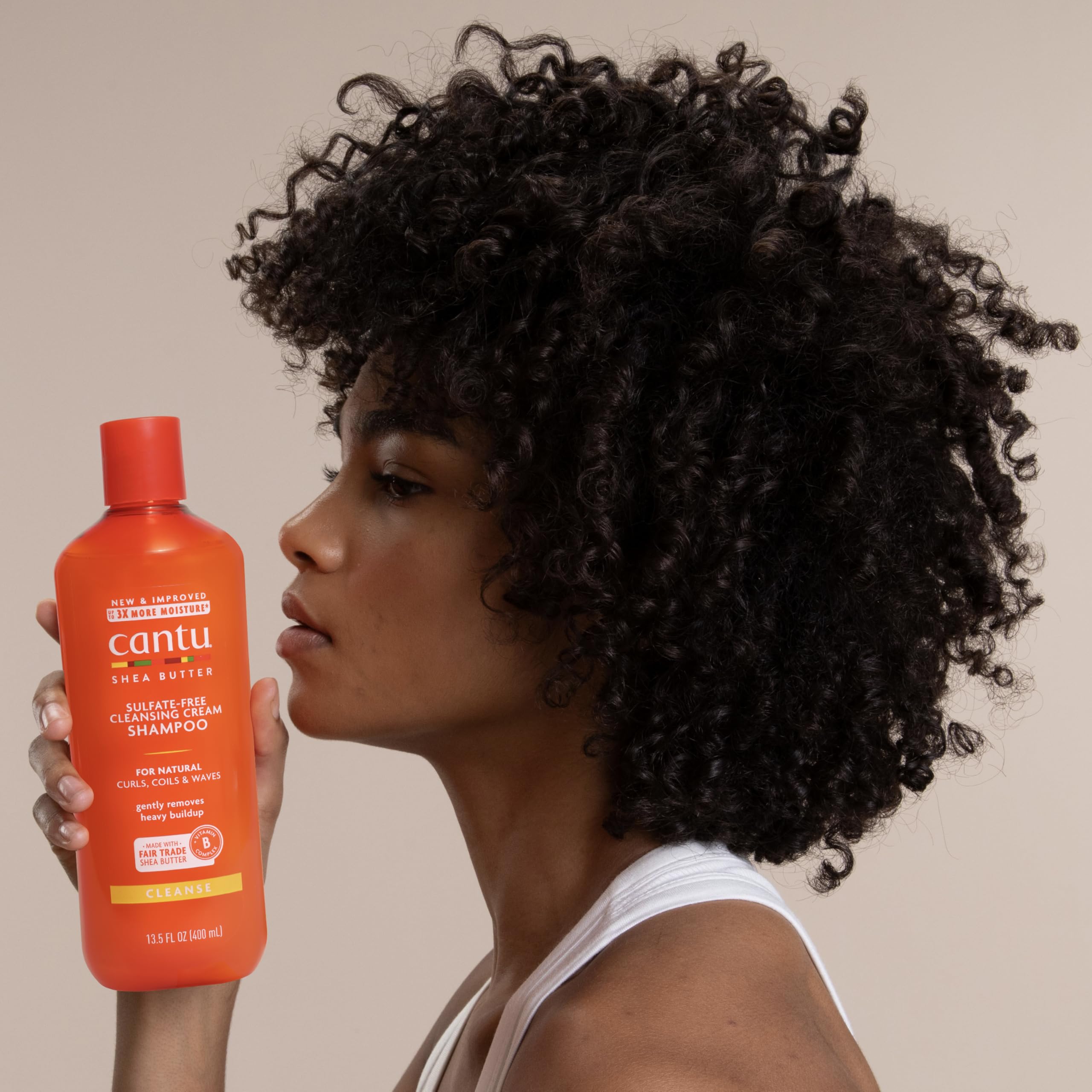 Cantu natural hair moisturizing shampoo container on clean shelf backdrop