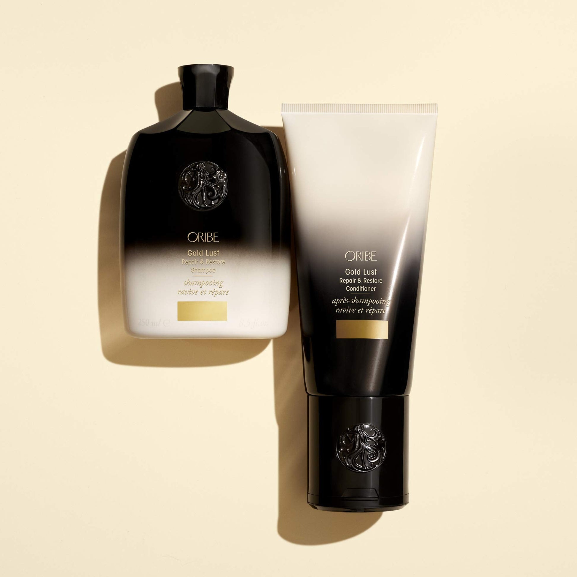 Oribe Gold Lust shampoo bottle held in hand showcasing the portable travel-friendly 8.5 ounce product size.
