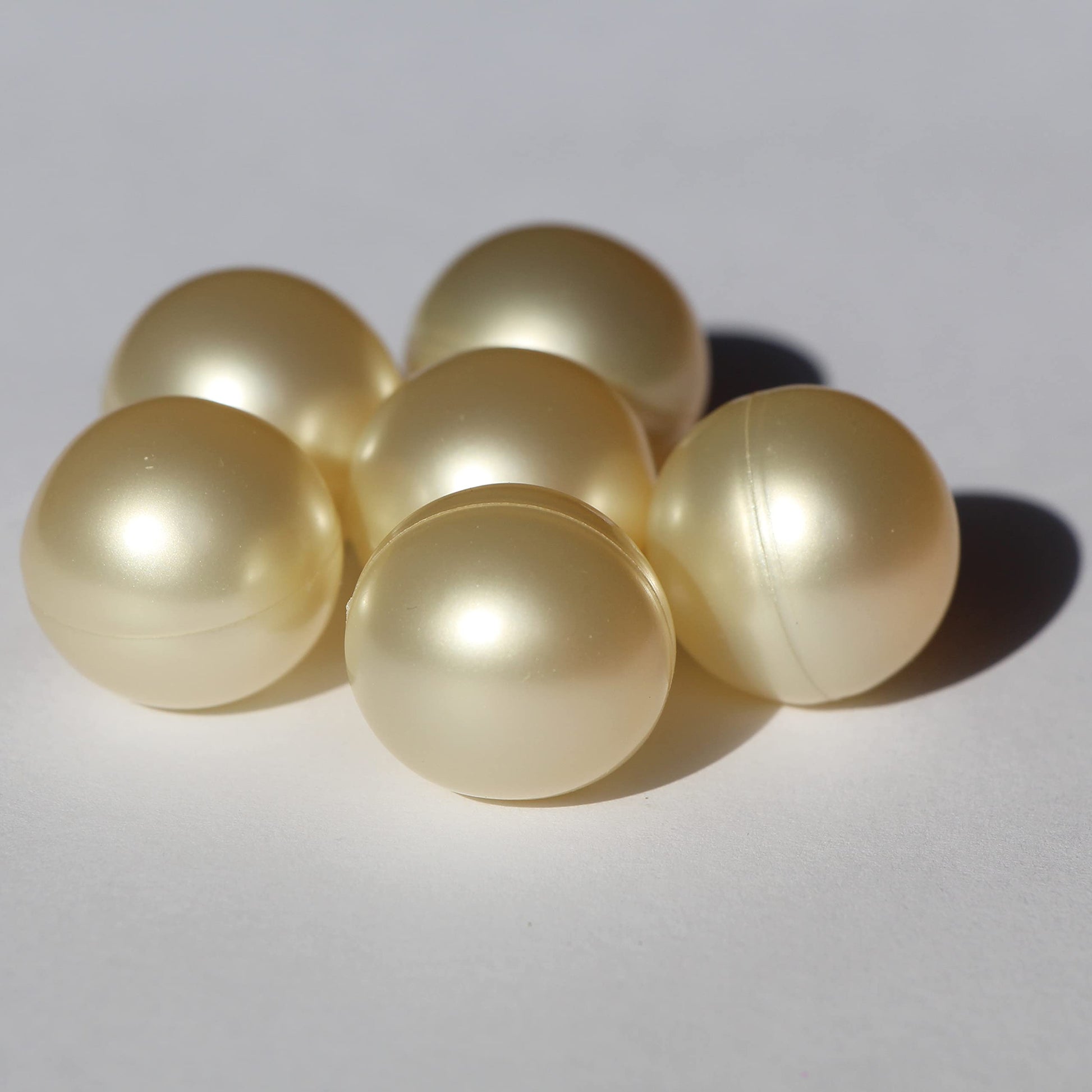Close up view of pearlescent ivory white bath oil beads showing smooth texture