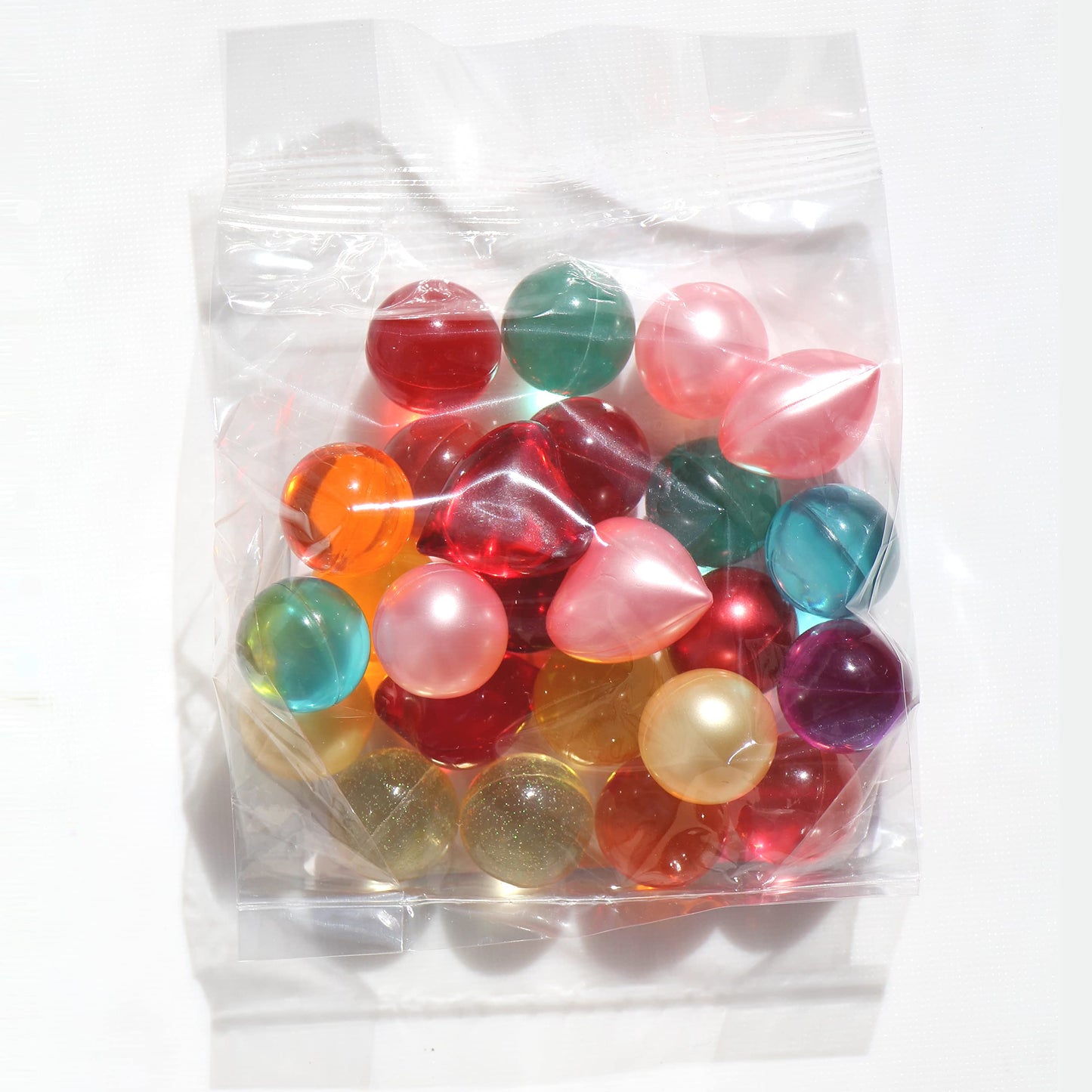 Nostalgic bath oil pearls in mixed colors held in a hand to show individual bead size.