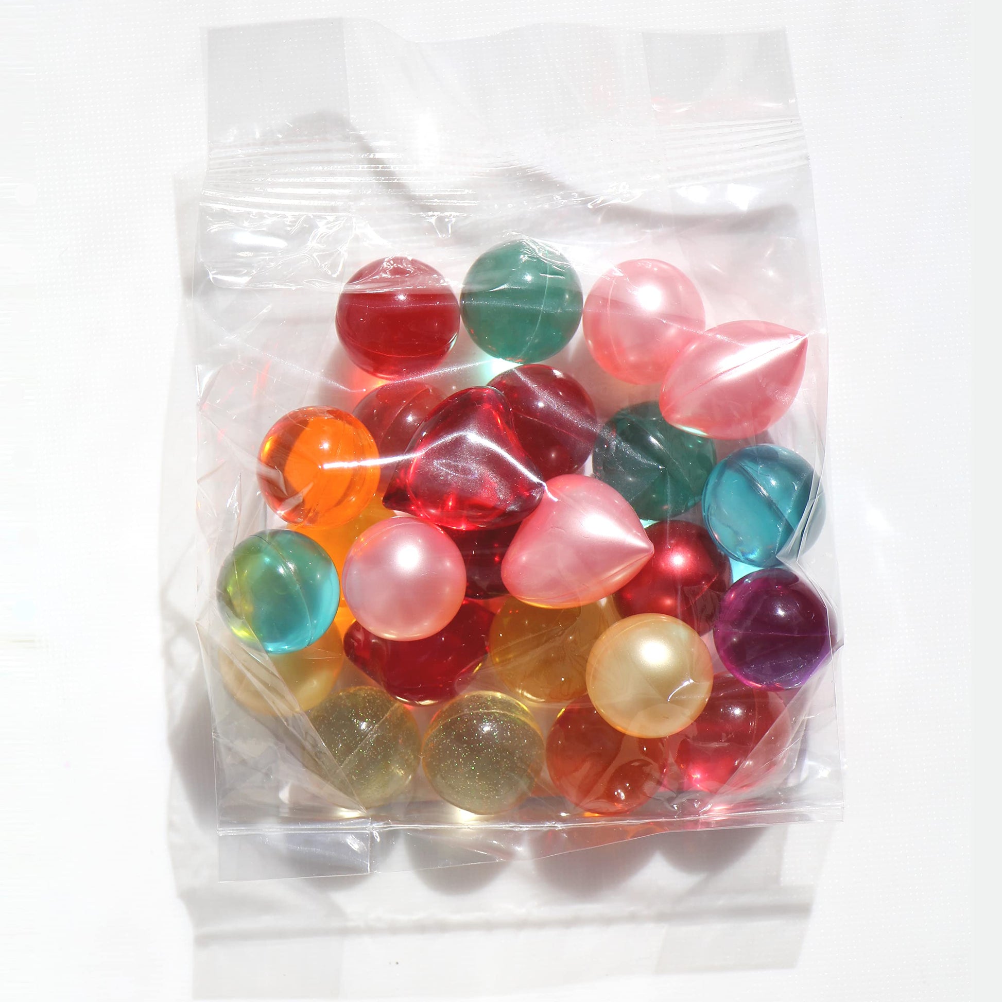 Nostalgic bath oil pearls in mixed colors held in a hand to show individual bead size.
