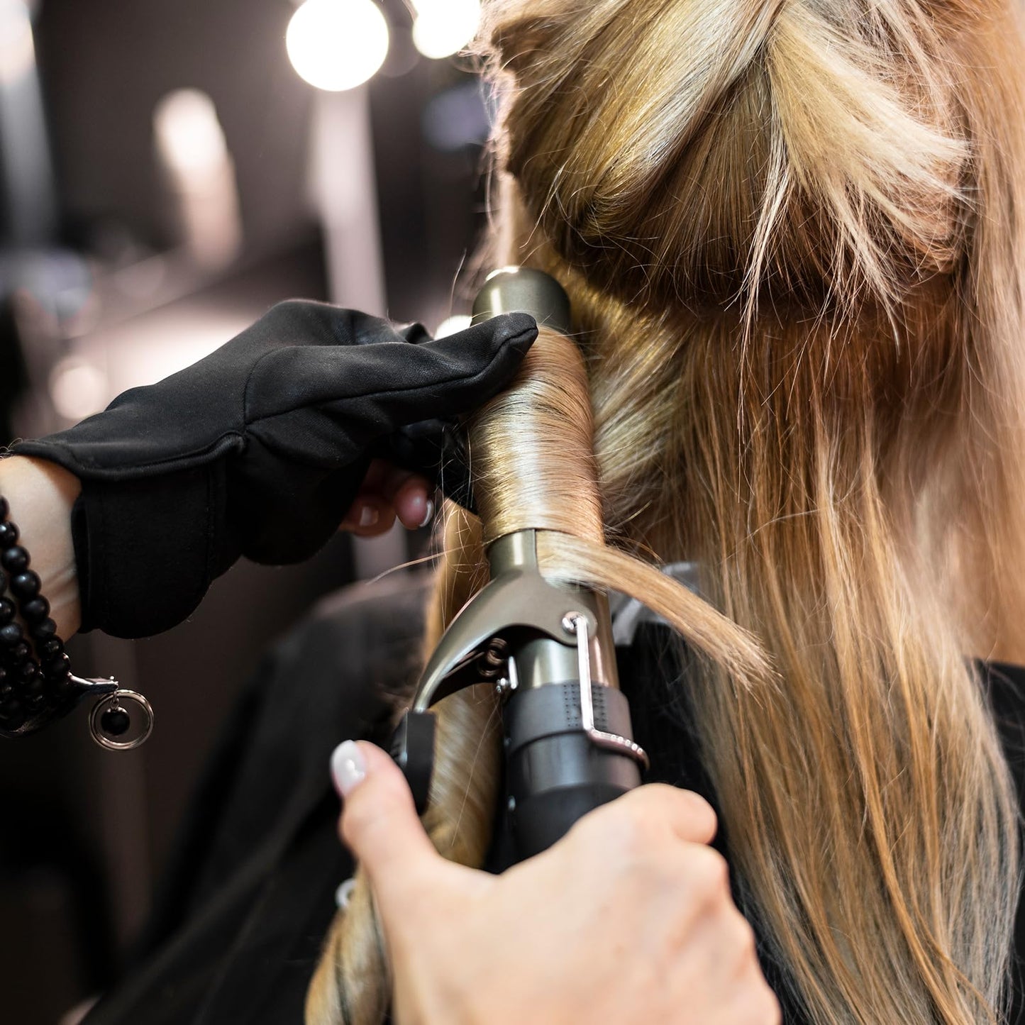 Black thermal styling glove protecting fingers from curling iron barrel heat