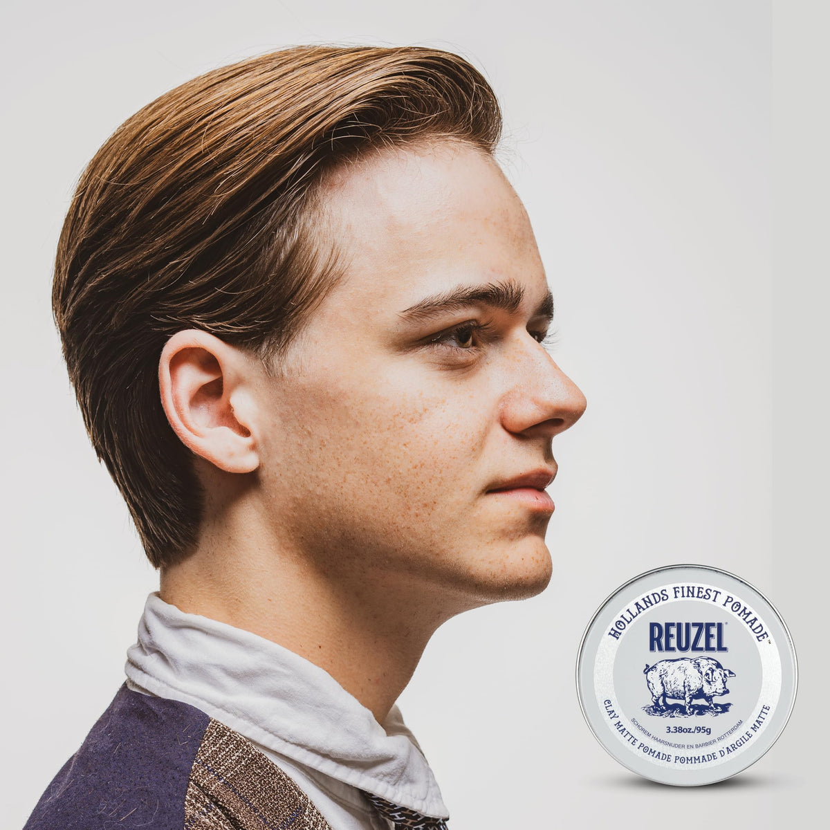 Open tin of Reuzel water-soluble styling wax displaying smooth clay pomade texture.