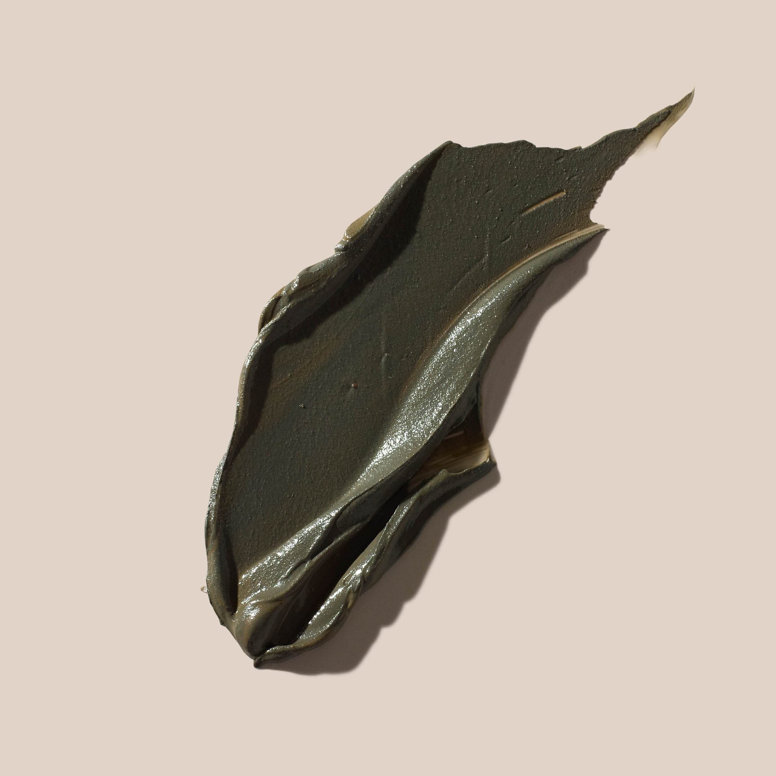 AHAVA creamy black mineral body mud being applied to skin for home spa detoxification.