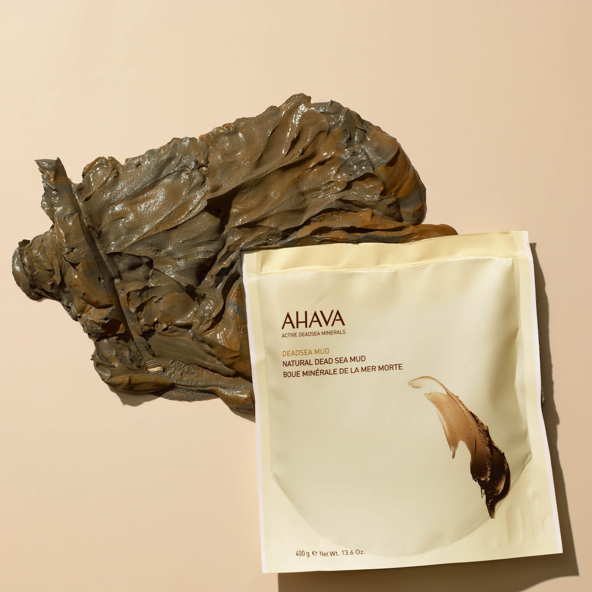 AHAVA vegan and paraben free body mud treatment pouch next to soothing spa elements.