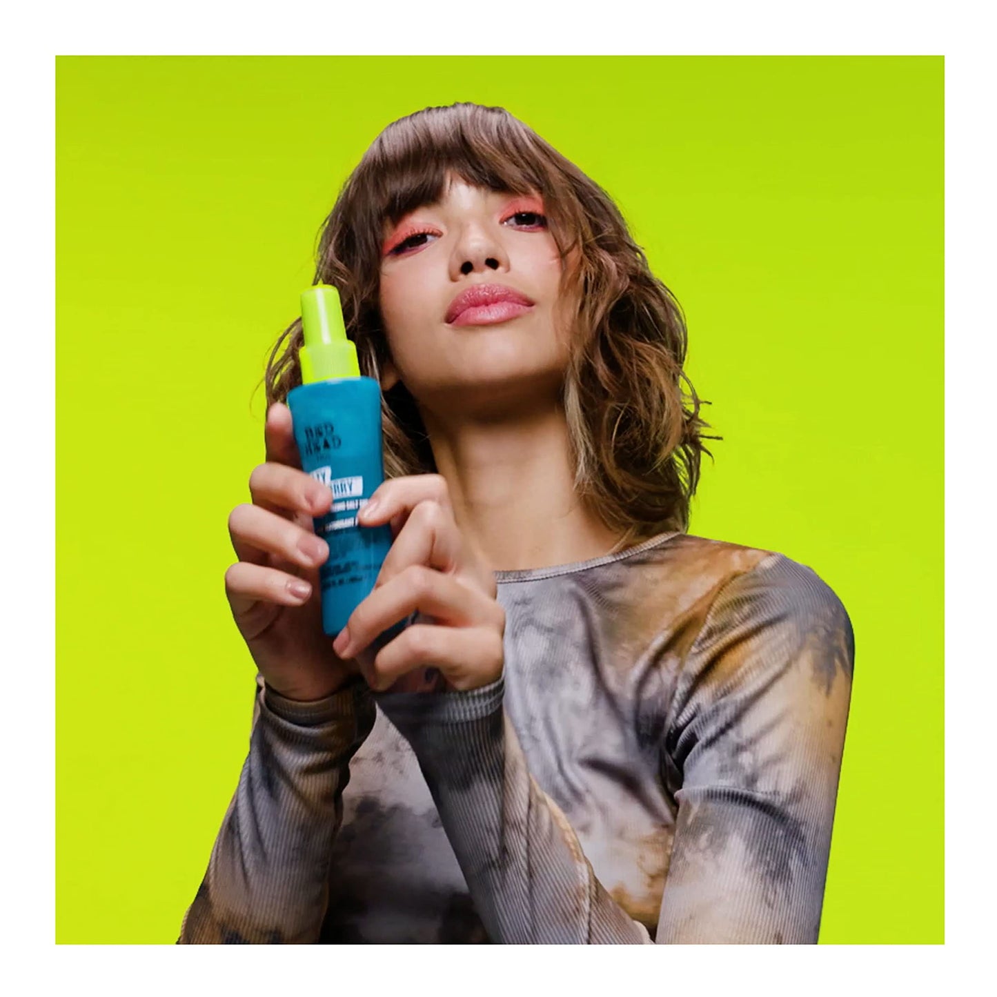 Applying Tigi Bed Head texturizing spray to hair