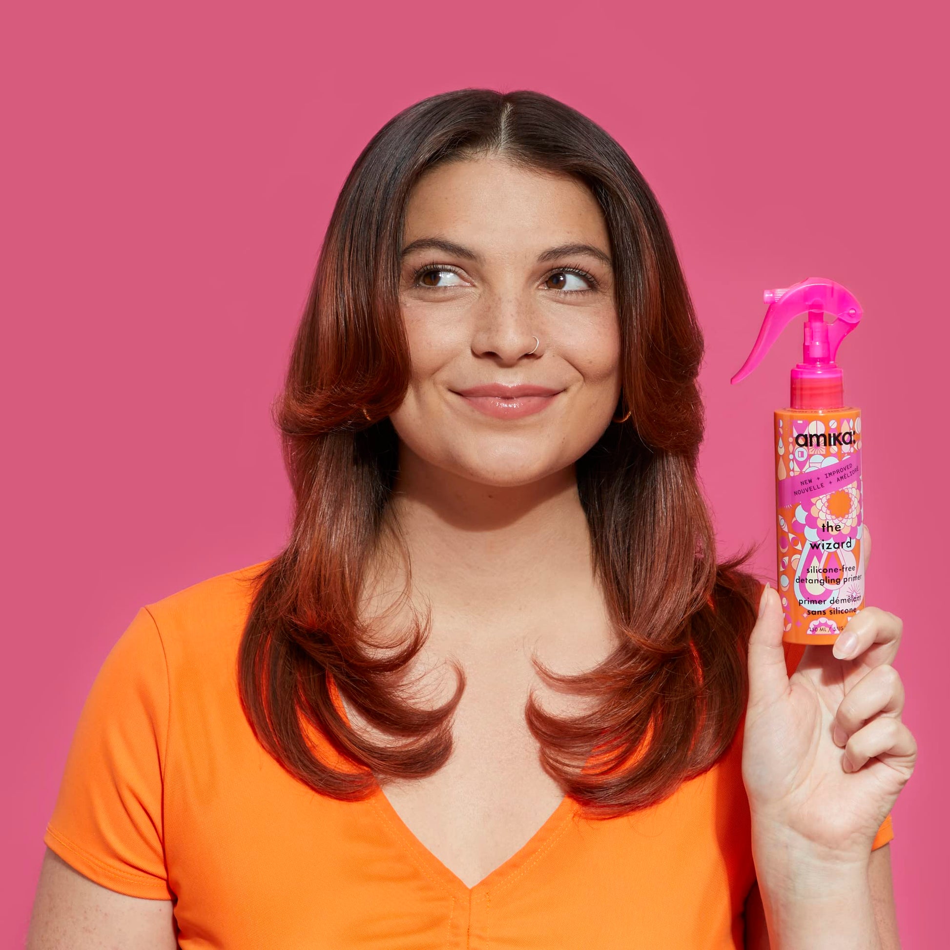 Amika anti frizz thermal shield spray placed on a clean flat surface backdrop