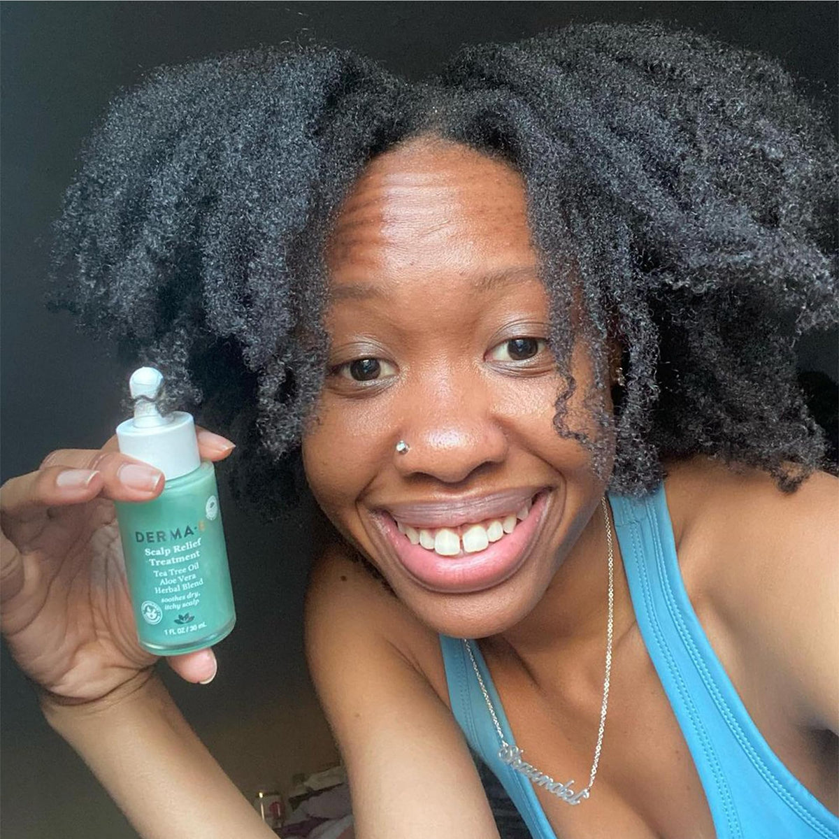 Derma E scalp serum bottle displayed with natural tea tree leaves