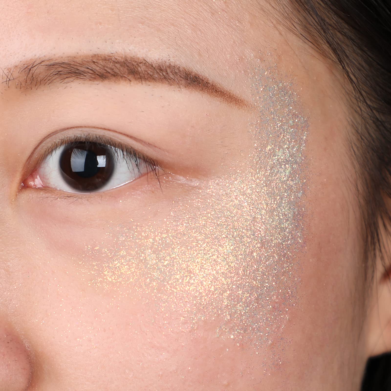 Model wearing fine iridescent face glitter gel on the cheekbones during a festival