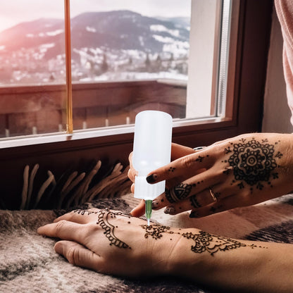 Fine tip needle applicator rendering intricate geometric lines for a temporary jagua tattoo design.