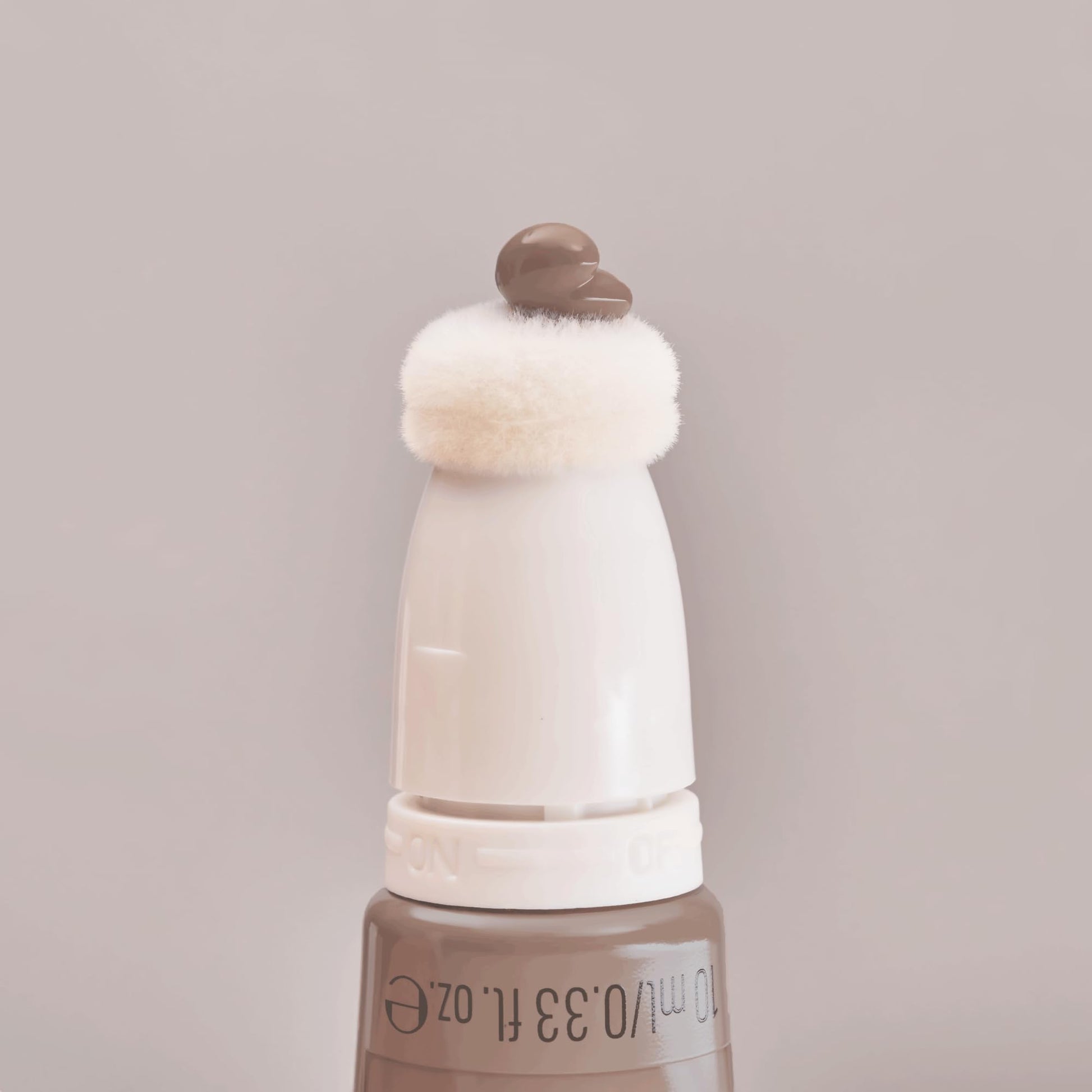A lifestyle shot of the authentic imported Essence liquid bronzer placed with other clean beauty products.