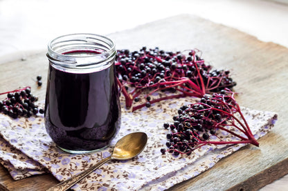 Whole dried black elderberries spilled next to the original packaging