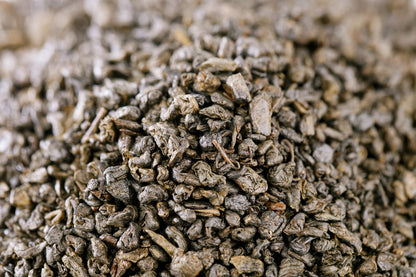 Brewed cup of organic gunpowder green tea with loose leaves