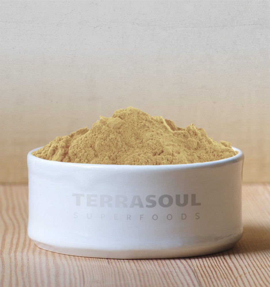 Raw green and brown Ayurvedic triphala herbal supplement powder displayed outside of its resealable packaging.