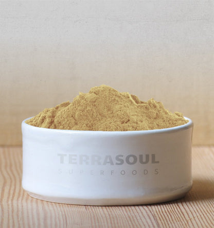 Raw green and brown Ayurvedic triphala herbal supplement powder displayed outside of its resealable packaging.