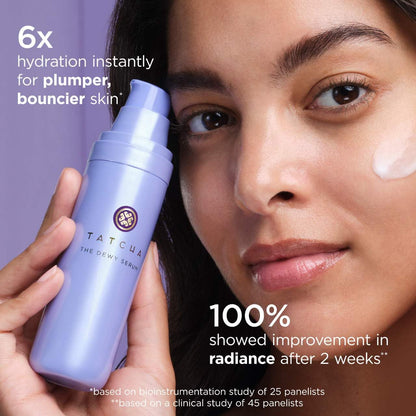 A hand holding the travel size Tatcha essence fluid to demonstrate the compact scale of the introductory kit.
