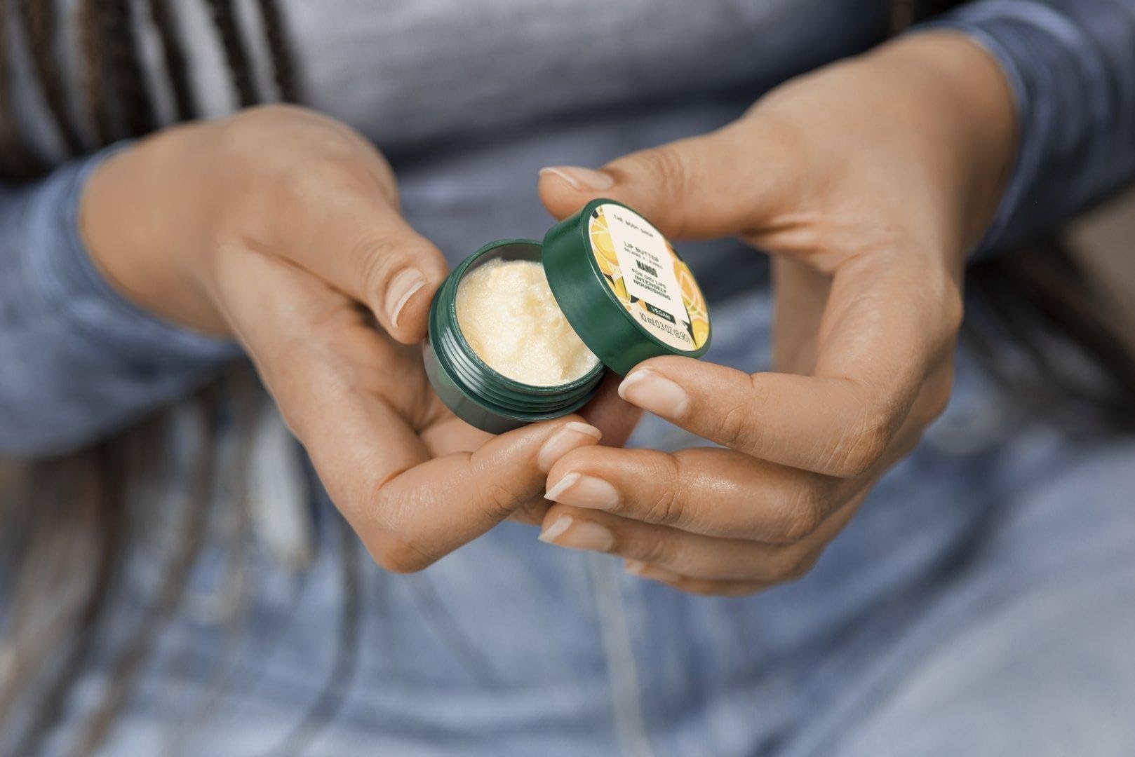 The Body Shop Mango Lip Butter held in hand for scale