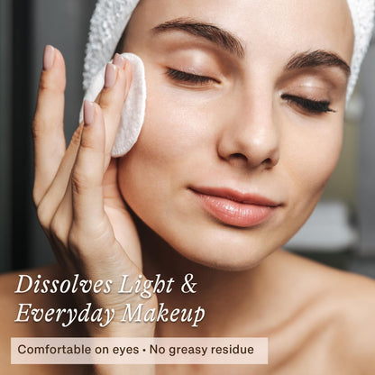 Natural eye and face makeup remover liquid poured on a reusable cotton pad