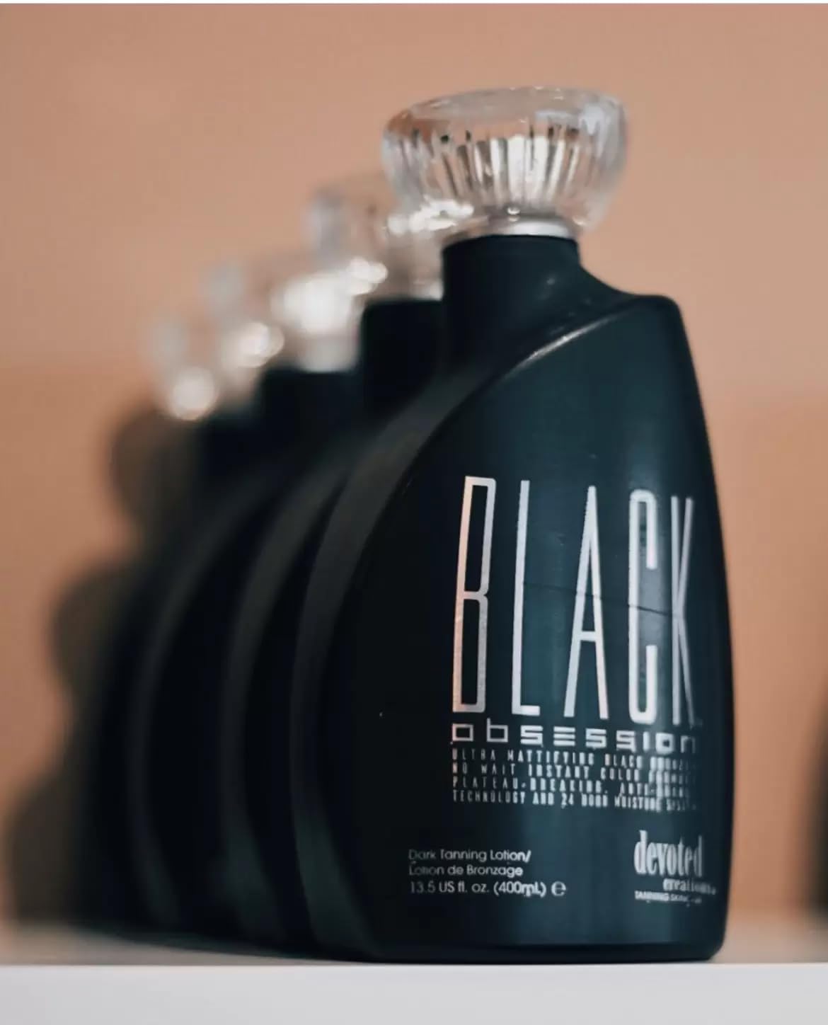 Side view of Devoted Creations Black Obsession tanning bottle