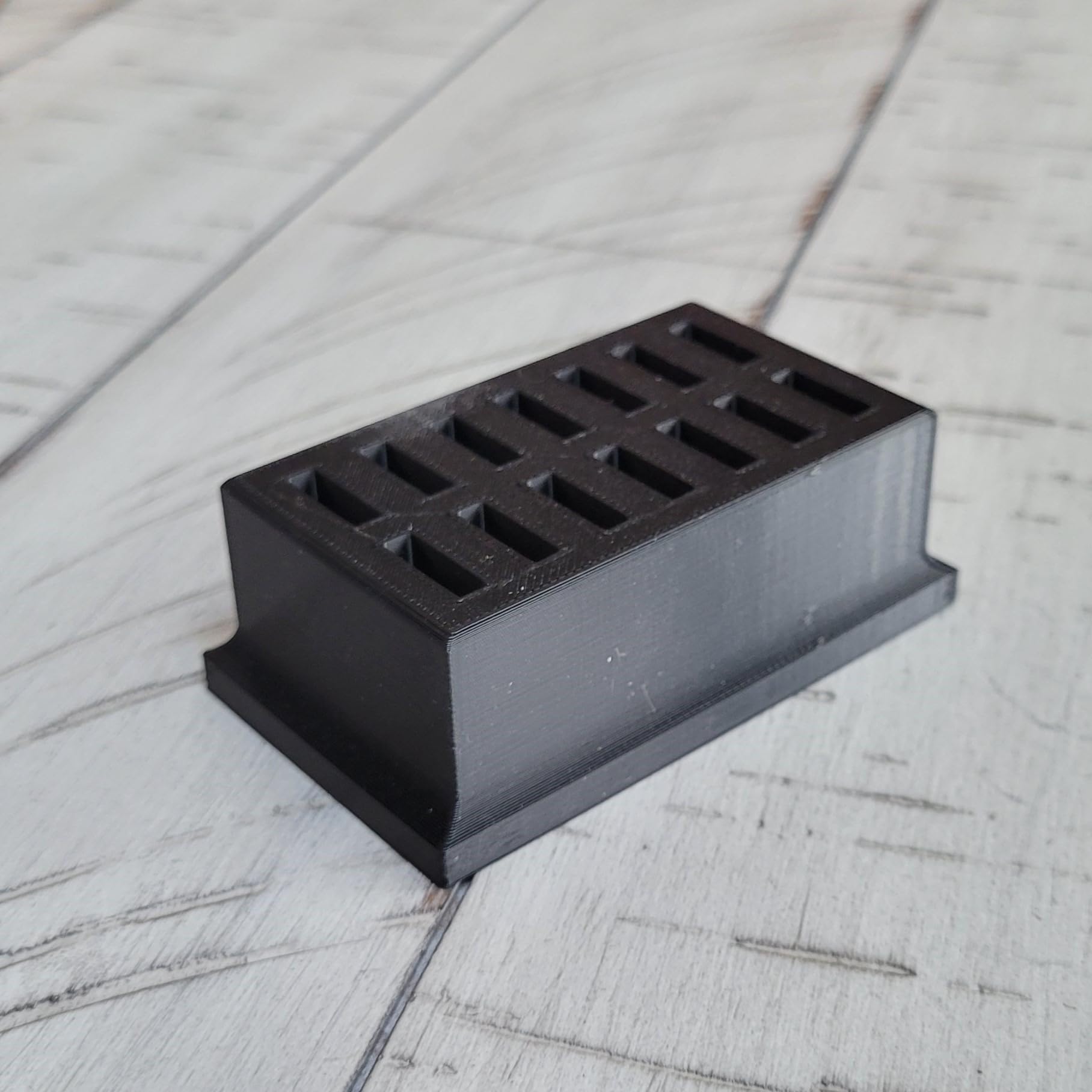 Top down angle of the Znet3D black plastic eye drop holder demonstrating the secure slot layout