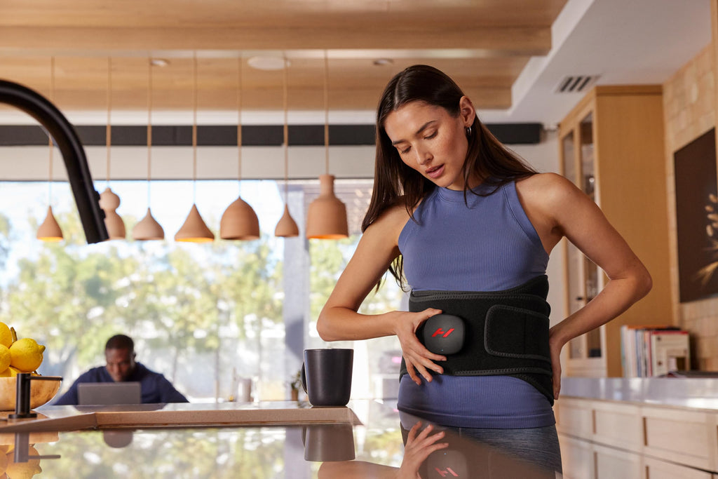 A user adjusting the heat level on the digital massager device for lower back soreness.