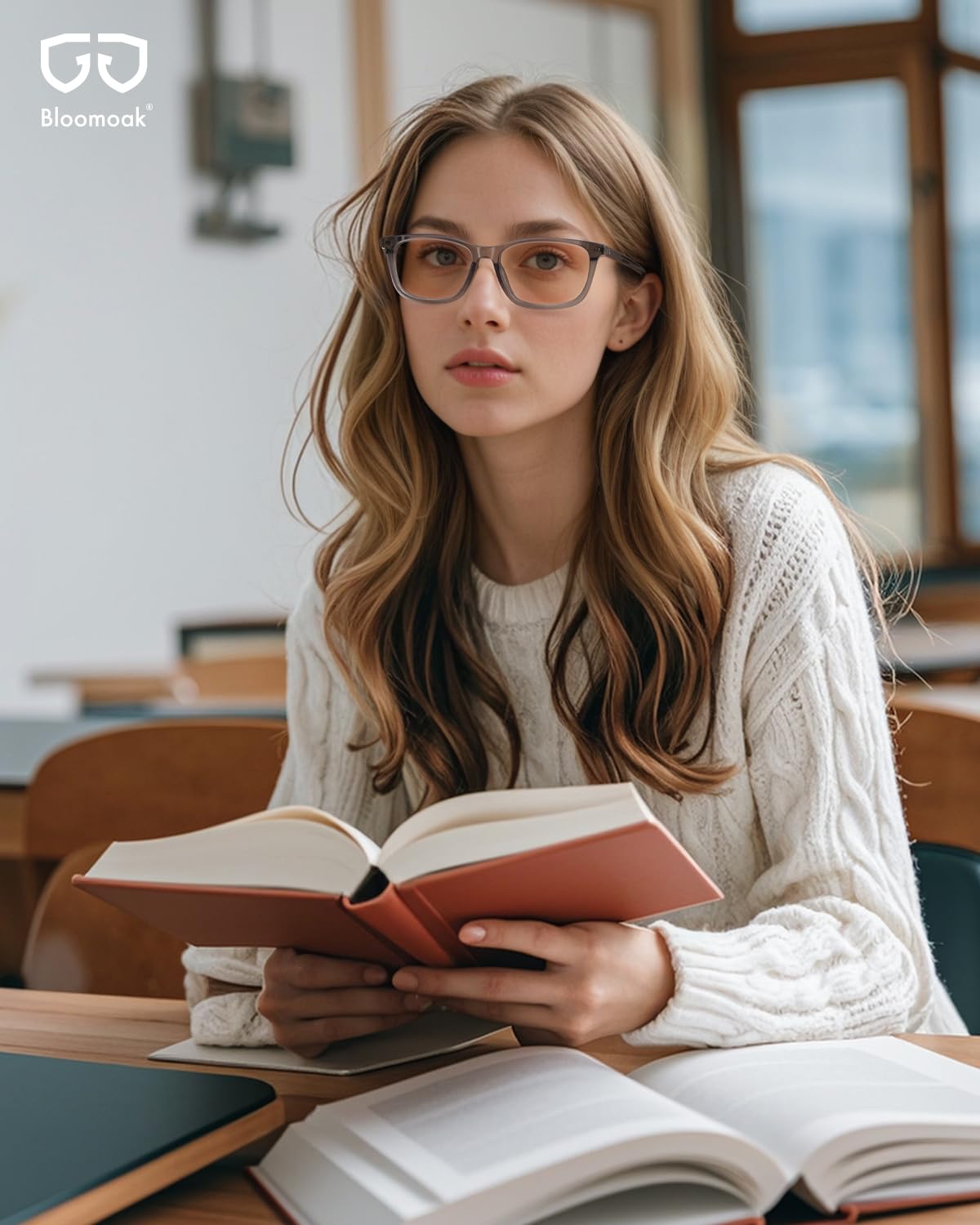 Side profile of Bloomoak rose-tinted migraine relief glasses on a desk.