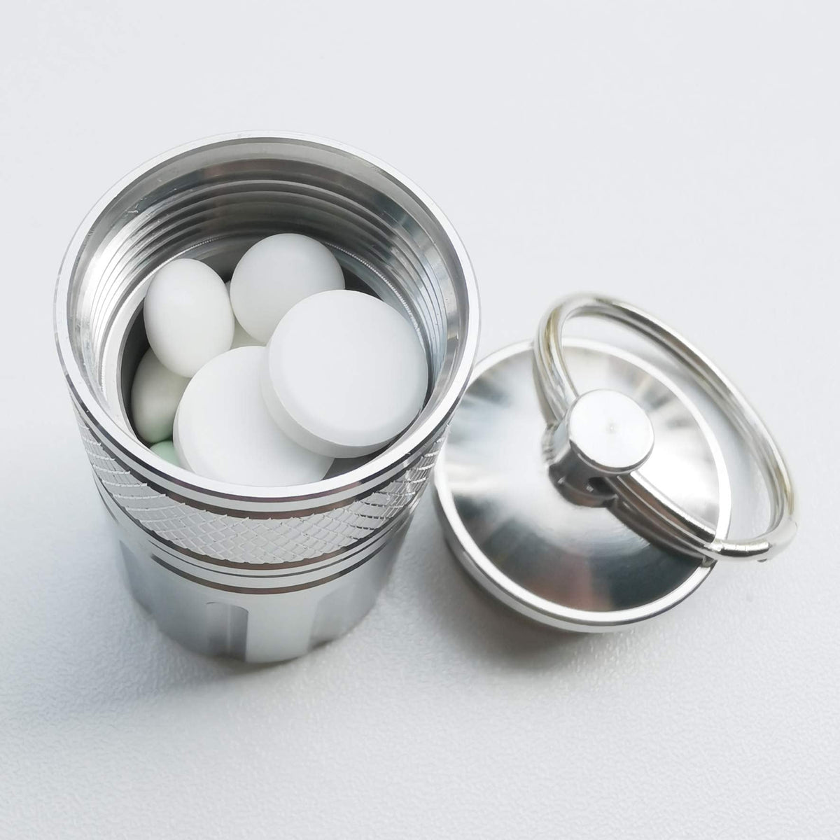 MEECN heavy duty travel medicine capsule being attached to a backpack using the included carabiner