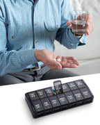 Sukuos premium imported black weekly pill organizer being filled with fish oil capsules.