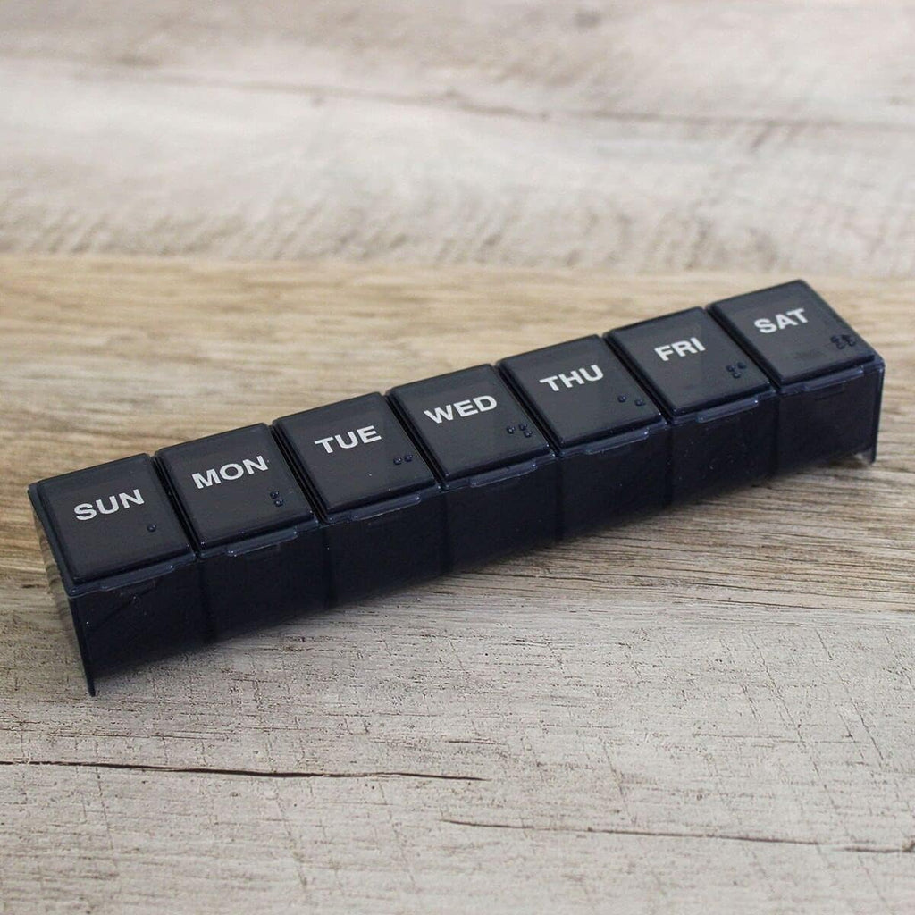 Ezy Dose daily pill case placed next to travel essentials showing how easily it fits into compact luggage compartments.