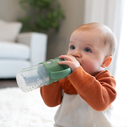 Baby holding Dr. Brown's narrow sippy bottle with silicone handles