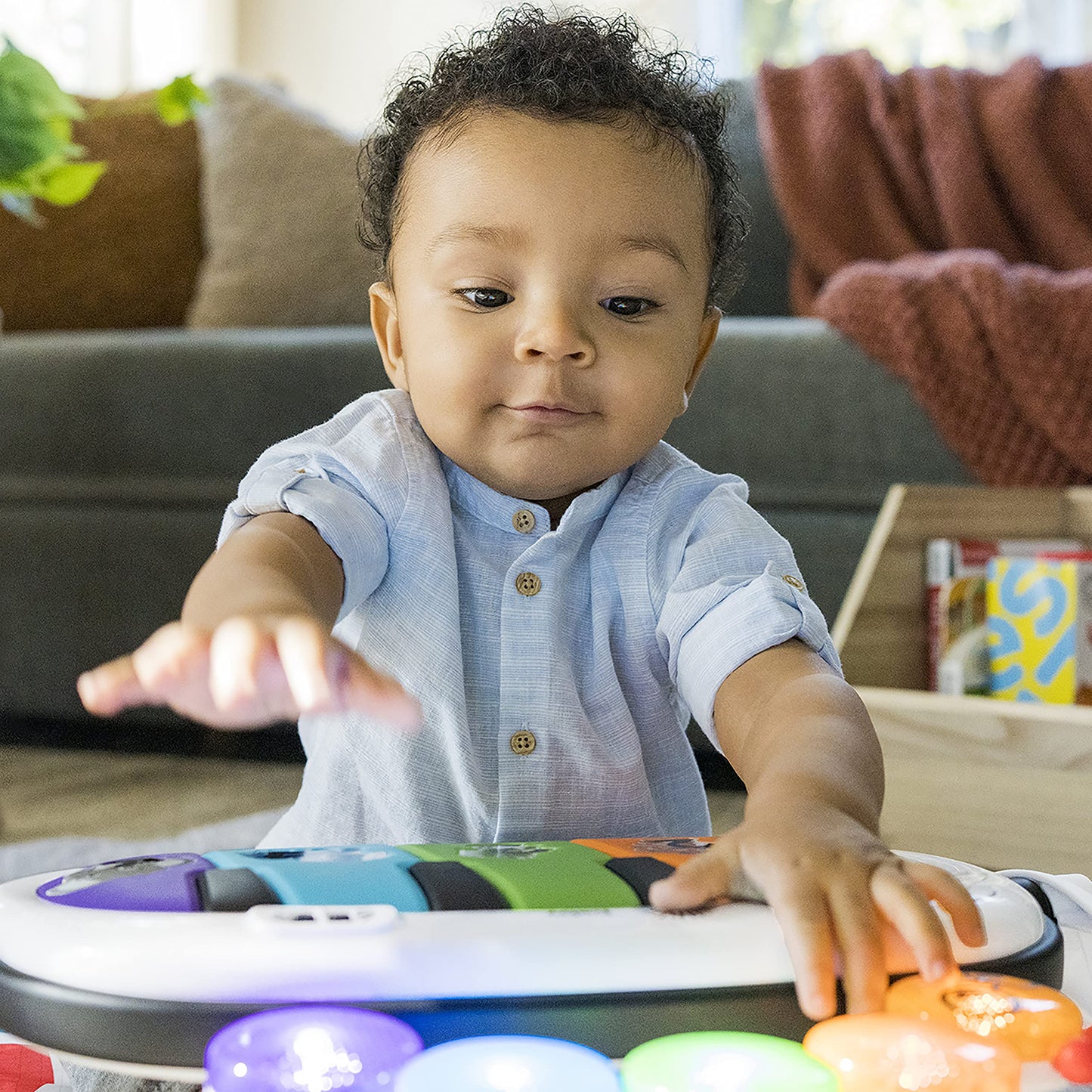 Infant activity mat layout demonstrating the tummy time mode with support pillow and attached sensory toys.