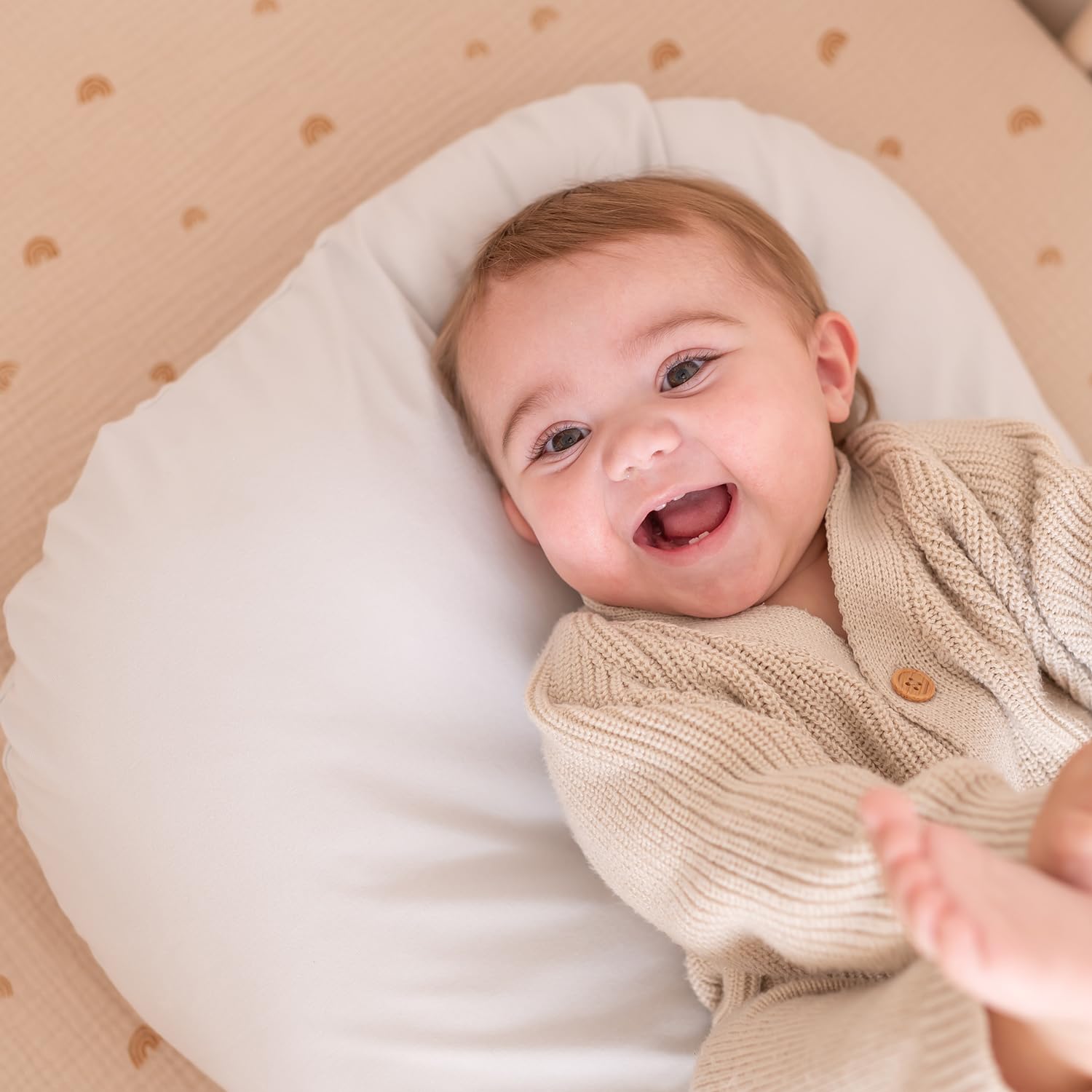 Parent placing baby on clean organic cotton lounger cover