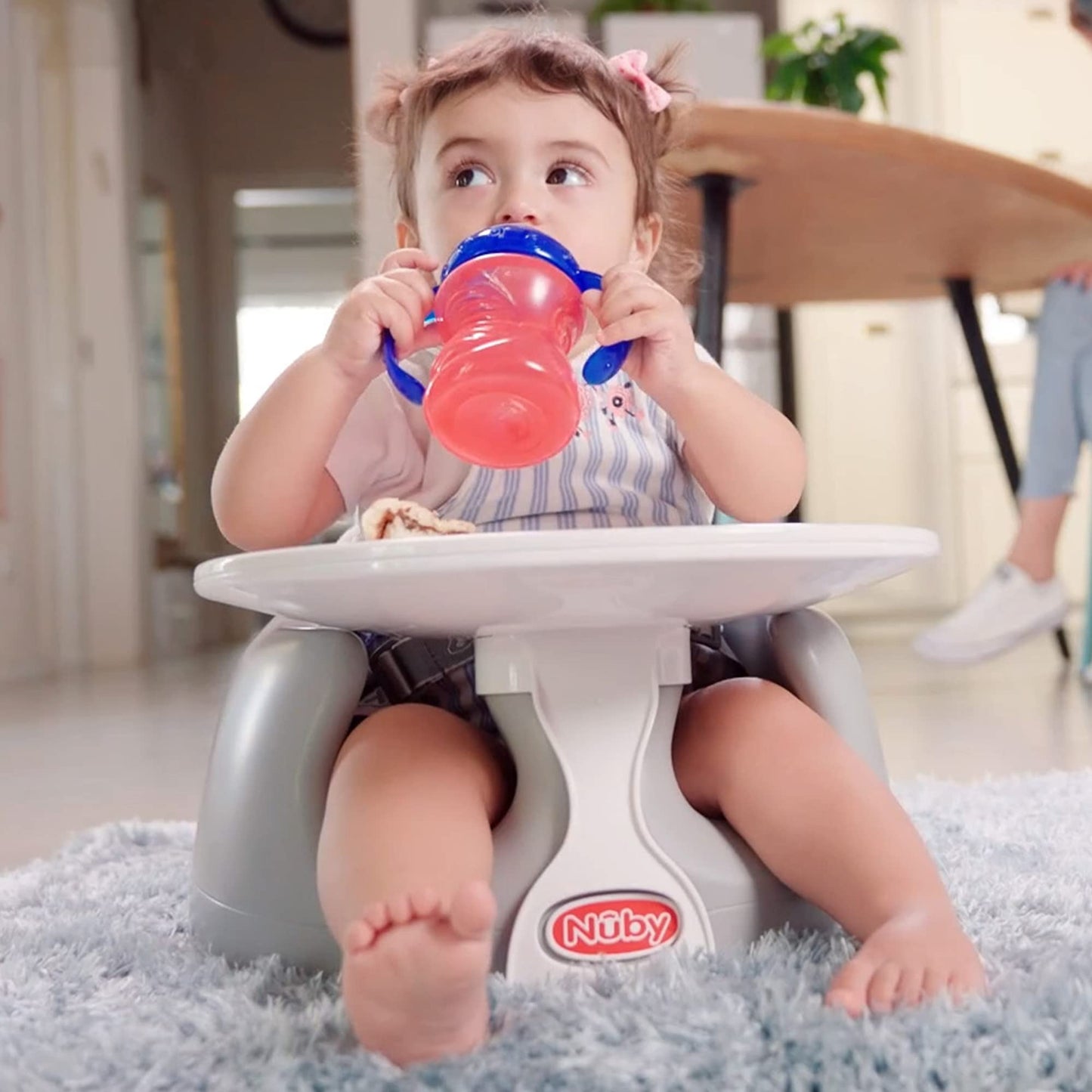 Baby sitting securely in Nuby portable floor chair