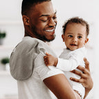 Parent using Egmao Baby burp cloth on shoulder for infant