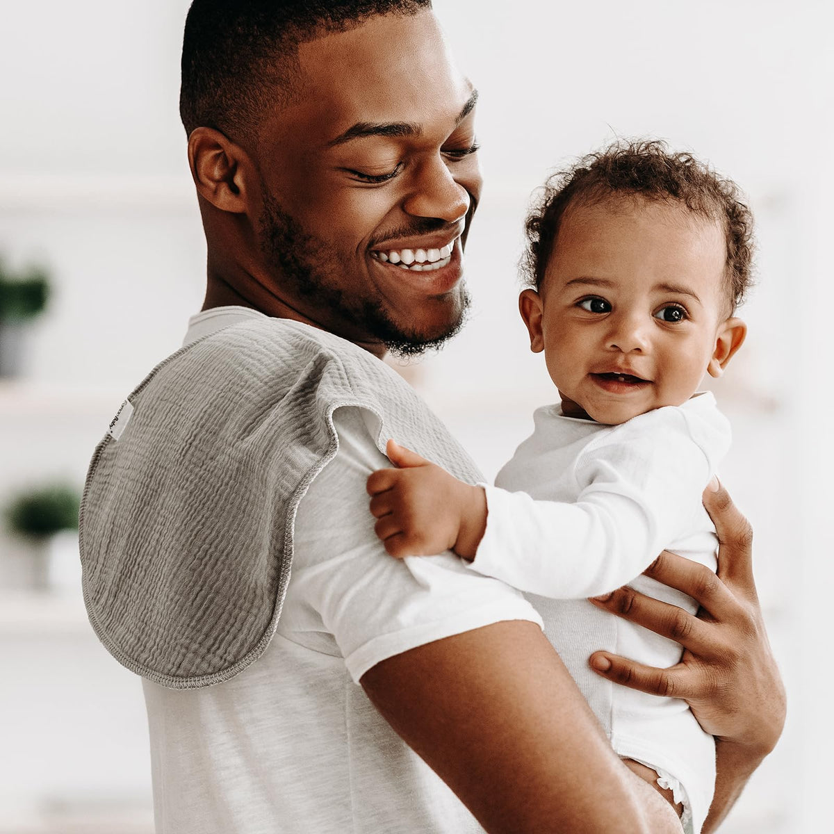 Parent using Egmao Baby burp cloth on shoulder for infant