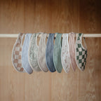 Infant wearing Mushie soft organic cotton muslin bib