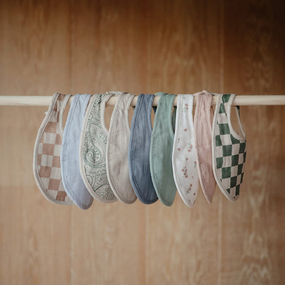 Infant wearing Mushie soft organic cotton muslin bib