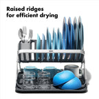 Oxo dish rack collapsed flat for compact storage inside a kitchen cabinet