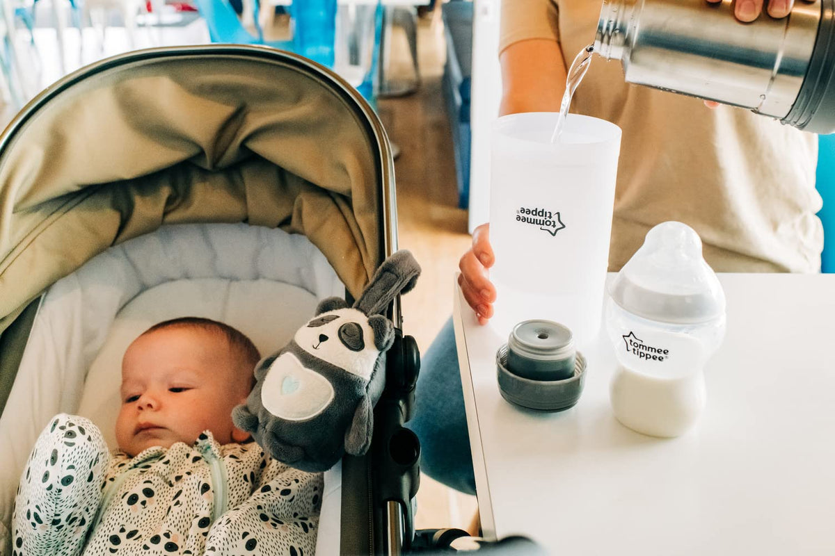 Lifestyle shot of feeding baby on the go with the portable warmer