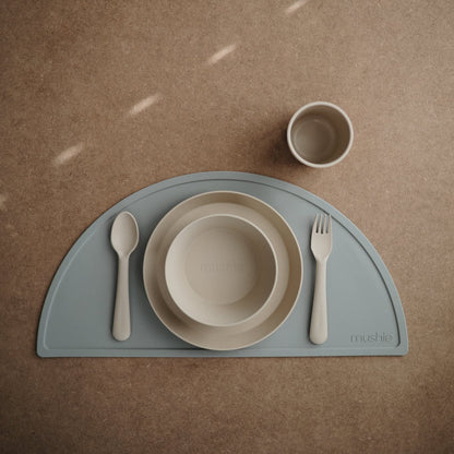 Toddler eating independently using Mushie round dinnerware bowl