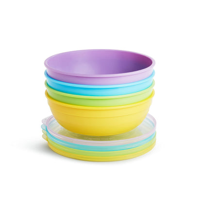 Munchkin baby bowls with lids and soft-tip spoons arranged on a table