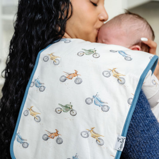 Oversized triple layer baby spit up cloth set draped over a shoulder